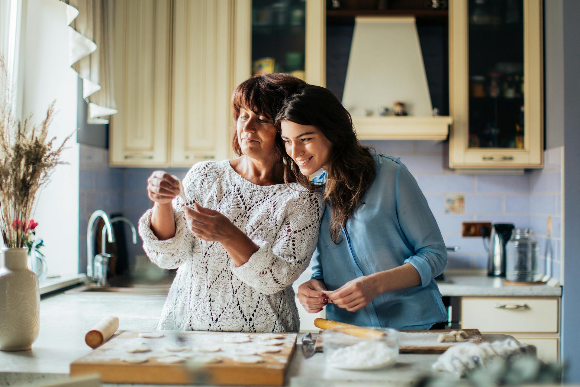 Woman In Blue Long Sleeve Shirt Beside Her Mother Two women talking together in a kitchen