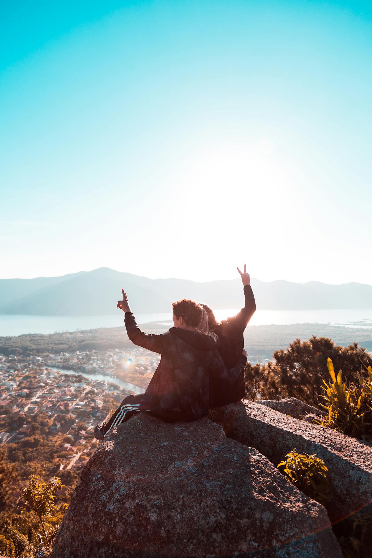 pexels-arthurbrognoli-2261016 A person standing outdoors with arms raised beside a lake